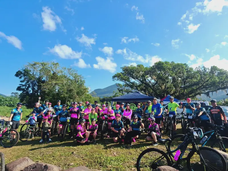 Grande grupo de ciclistas reunido ao ar livre antes do passeio, com as bikes ao redor