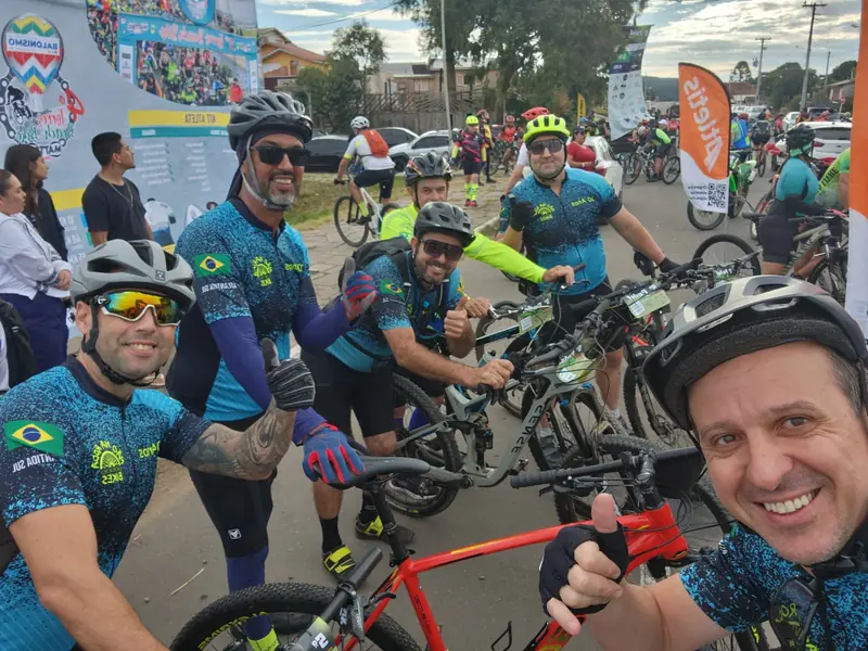 Selfie de ciclistas sorrindo e fazendo sinal de positivo durante o passeio