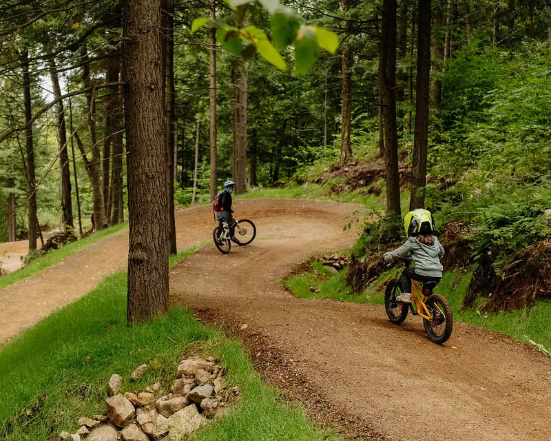 Mãe e filho pedalando juntos em trilha de terra