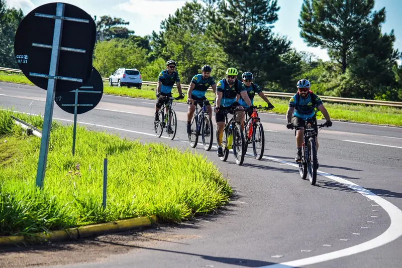 Pelotão de ciclistas da Mão na Roda Bikes pedalando juntos em estrada do litoral gaúcho